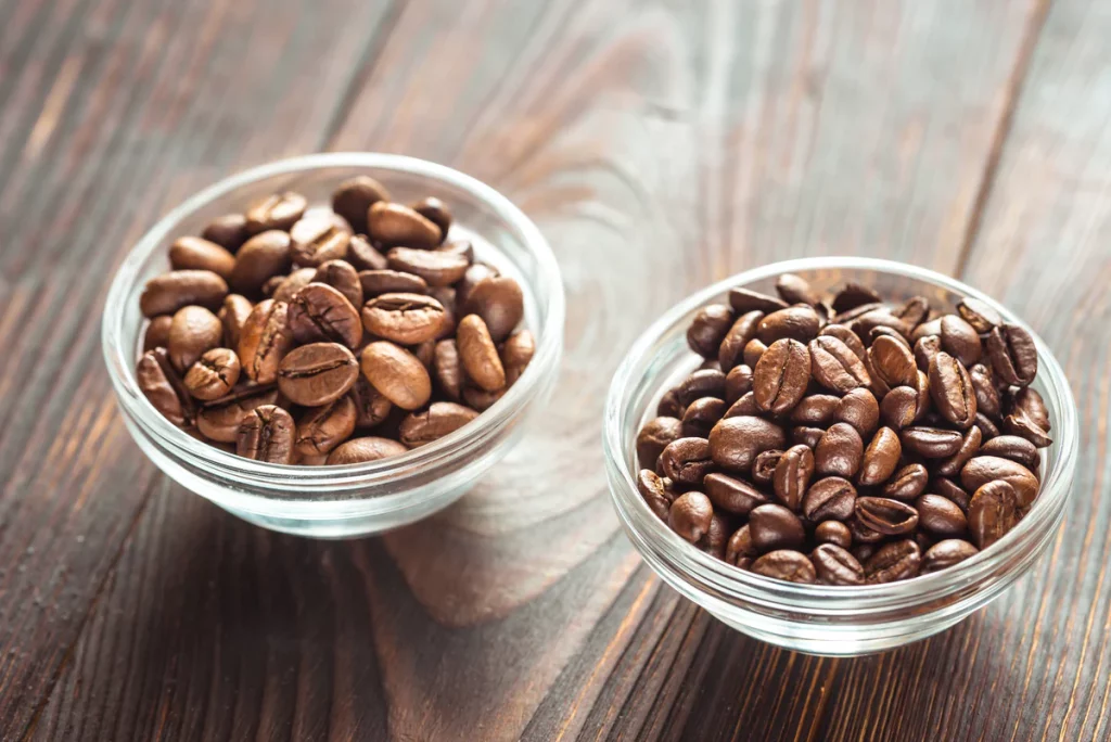 Deux petits bols de grains de café d'Arabica et Robusta.