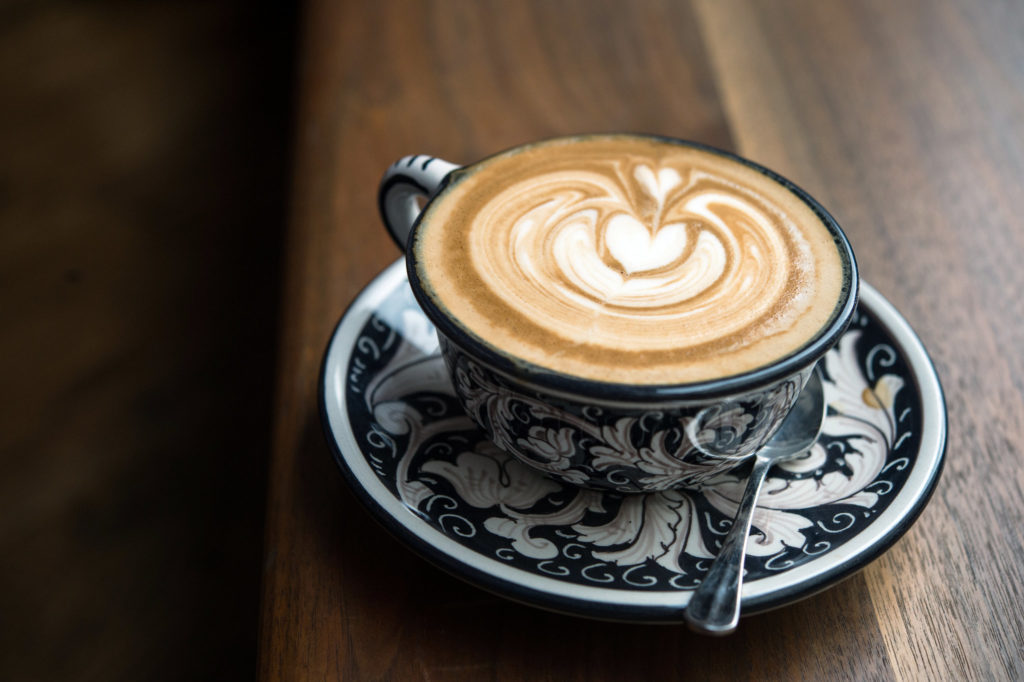 Café Cappuccino dans une tasse noire avec de la mousse qui dessine un coeur. 