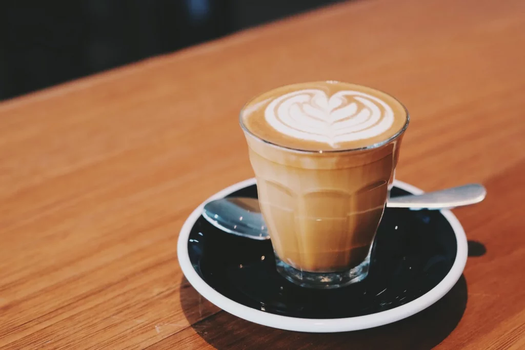 Un café Piccolo préparé dans un verre de café sur une soucoupe noire.