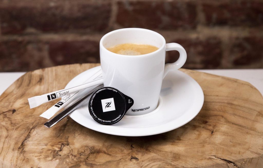 Tasse de café Lungo sur une soucoupe avec du sucre et du lait sur le côté.