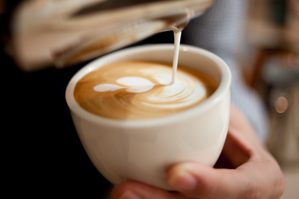 Un peu de lait qui coule dans une tasse d'un café Latte