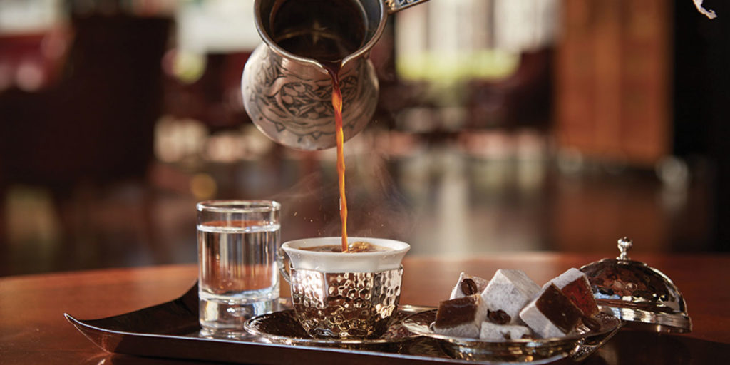 Café turc versé non filtré d'un ibrik dans une tasse turque traditionnelle.