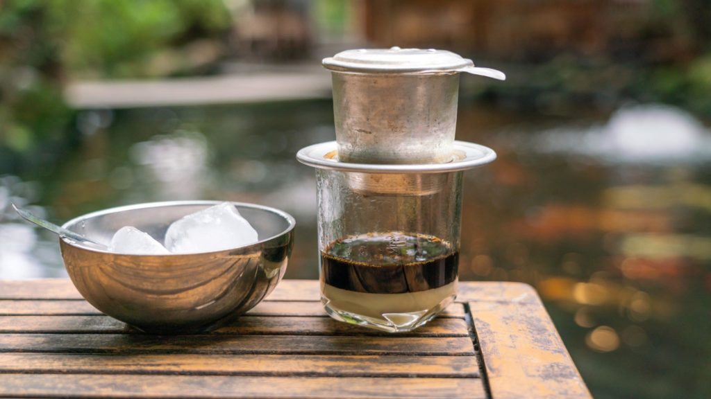 Café vietnamien infusé, préparé dans une tasse en verre avec des glaçons sur le côté