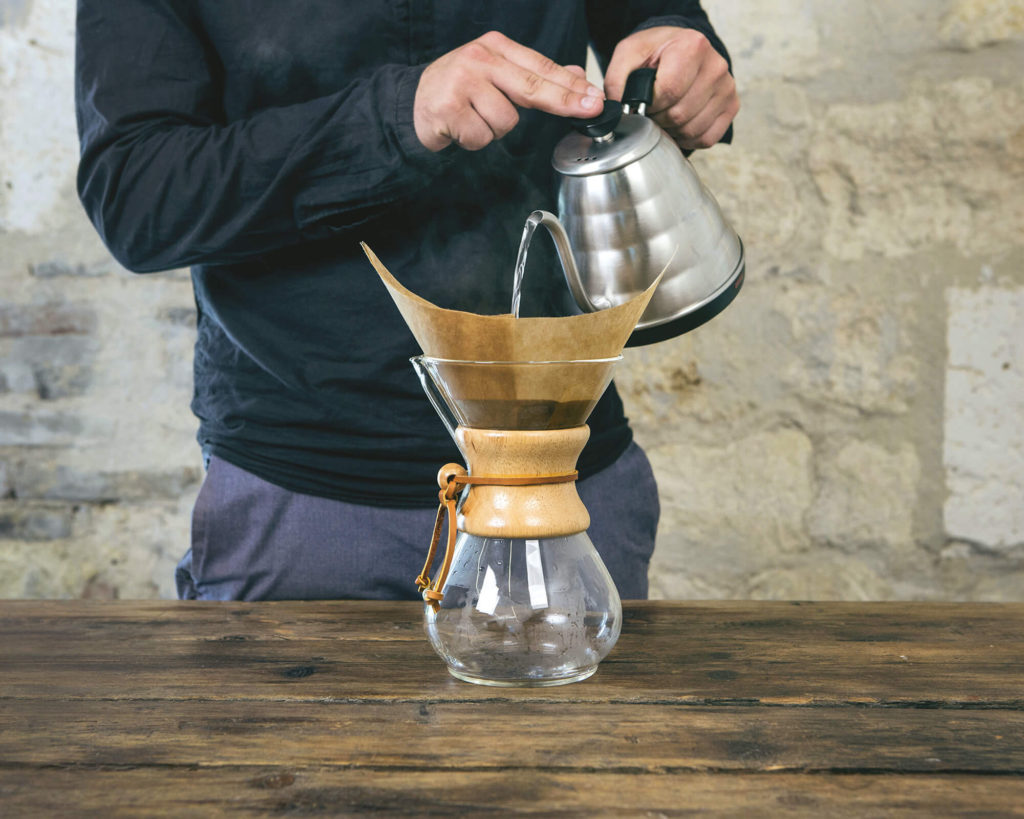 De l'eau bouillante coule dans un chemex afin de préparer un café