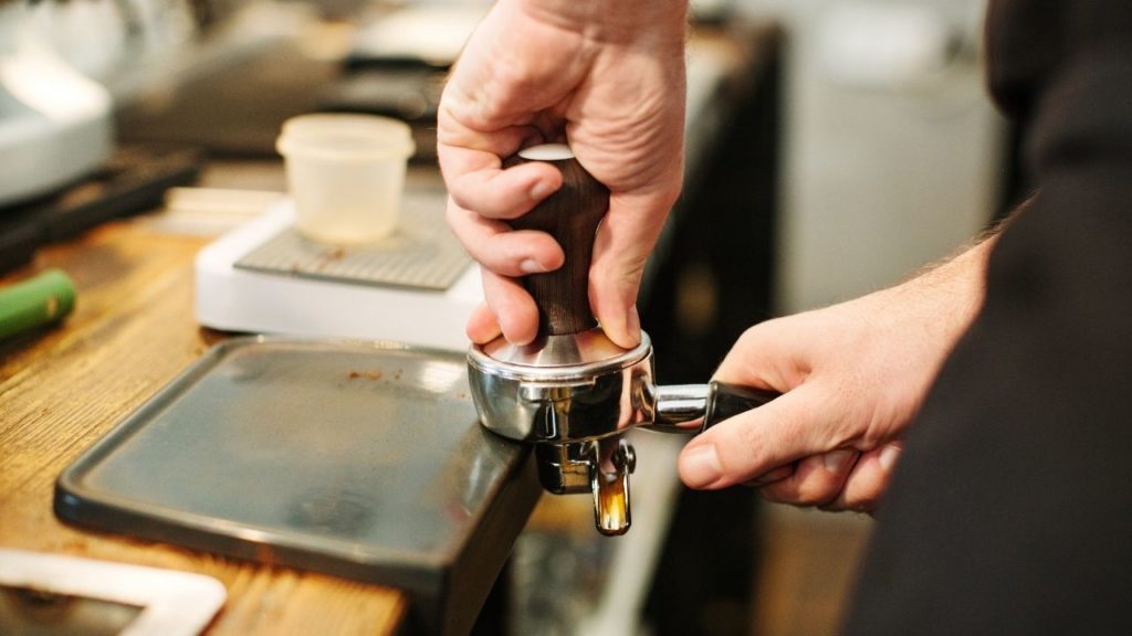 Une personne qui tasse son café avec un tampon avec une pression d'environ 20 kg.